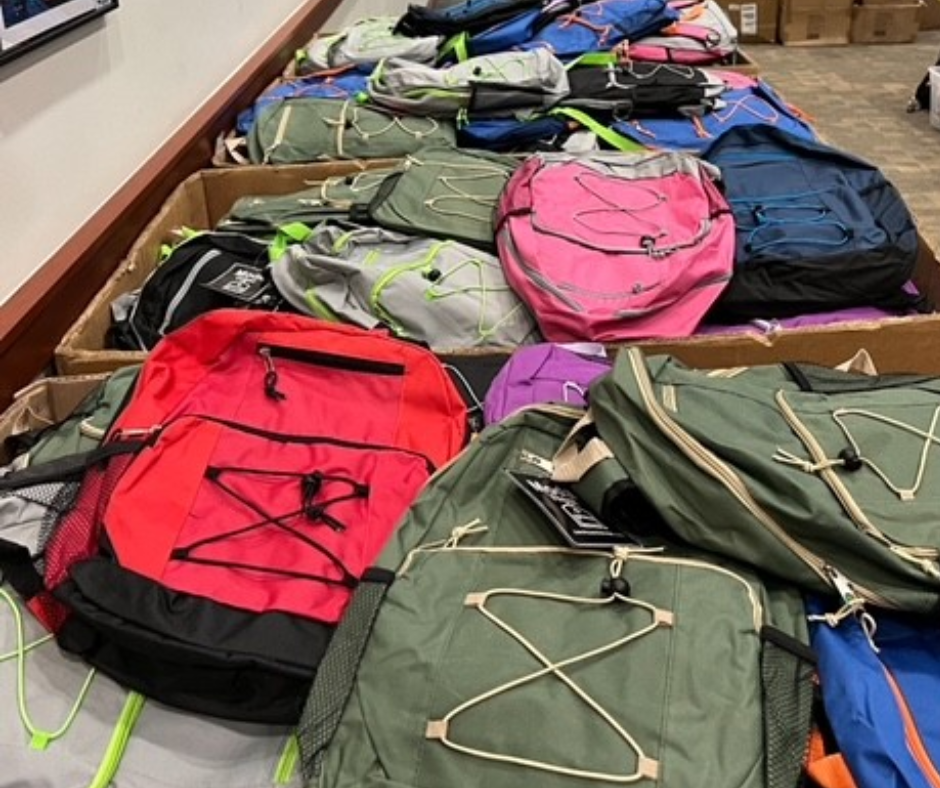 hundreds of backpacks stacked in large boxes