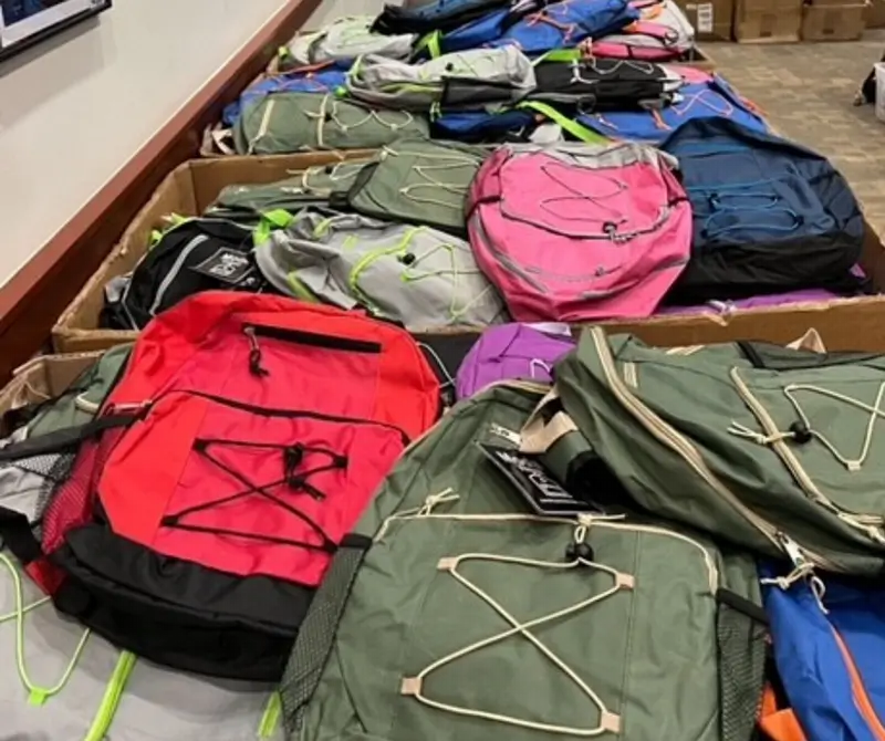 hundreds of backpacks in large rolling boxes ready to go to students in need